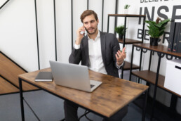 real estate agent talking on a mobile phone with a client in the office sitting in front of a laptop