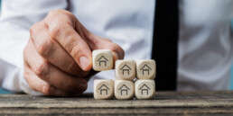 Front view of real estate agent stacking wooden dices with house symbols on them in a conceptual image.