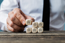 Front view of real estate agent stacking wooden dices with house symbols on them in a conceptual image.
