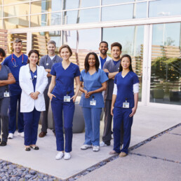 Healthcare team with ID badges stand outdoors