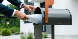 man in suit putting mail in mailbox