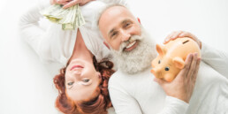 smiling mature couple with dollar banknotes and piggy bank