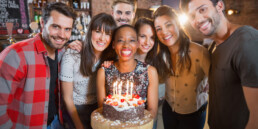 Portrait of happy friends holding birthday cake in restaurant